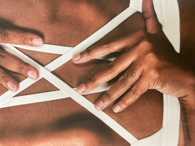Practitioner's hands and white sports-bra straps on a client's back during a session